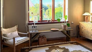 Una habitación con una silla de madera, un radiador, un escritorio con una planta y un aparador.