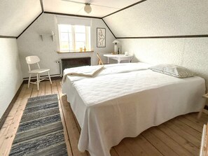 Ein Schlafzimmer mit einem großen Bett, einem Sessel, einem kleinen Tisch und einem Fenster.