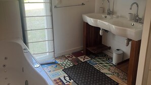 A bathroom with a bathtub, two sinks, a mirror, and a patterned floor. - Near La Baule/Historical center.  Villa located in a bubble of Serenity. (Guérande)