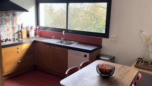 A kitchen with wooden cabinets, a sink, and a window with a view of trees. - Near La Baule/Historical center.  Villa located in a bubble of Serenity. (Guérande)