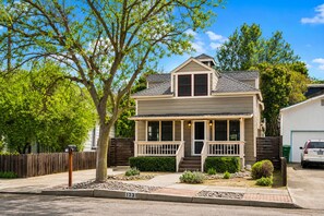 A two-story house with a front porch, a garage, and a well-maintained front yard. - Spa + BBQ + Big Backyard | Walk to Downtown Paso | Backyard Vines on Olive (Paso Robles)