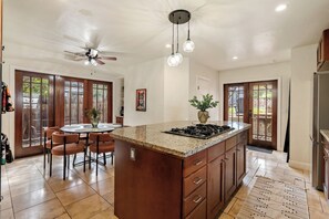 A spacious kitchen with a large island, wooden cabinets, and a ceiling fan. - Spa + BBQ + Big Backyard | Walk to Downtown Paso | Backyard Vines on Olive (Paso Robles)