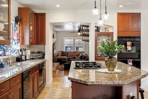 A kitchen with granite countertops, wooden cabinets, a central island, and a dining area with a sofa and coffee table.