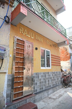 A building with a sign reading 'RAJU INN' and a metal door with a decorative design. - Raju Inn (Puri)