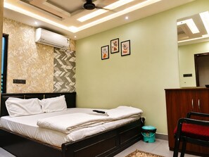 A bedroom with a bed, a wardrobe, a mirror, and a ceiling fan. - Raju Inn (Puri)