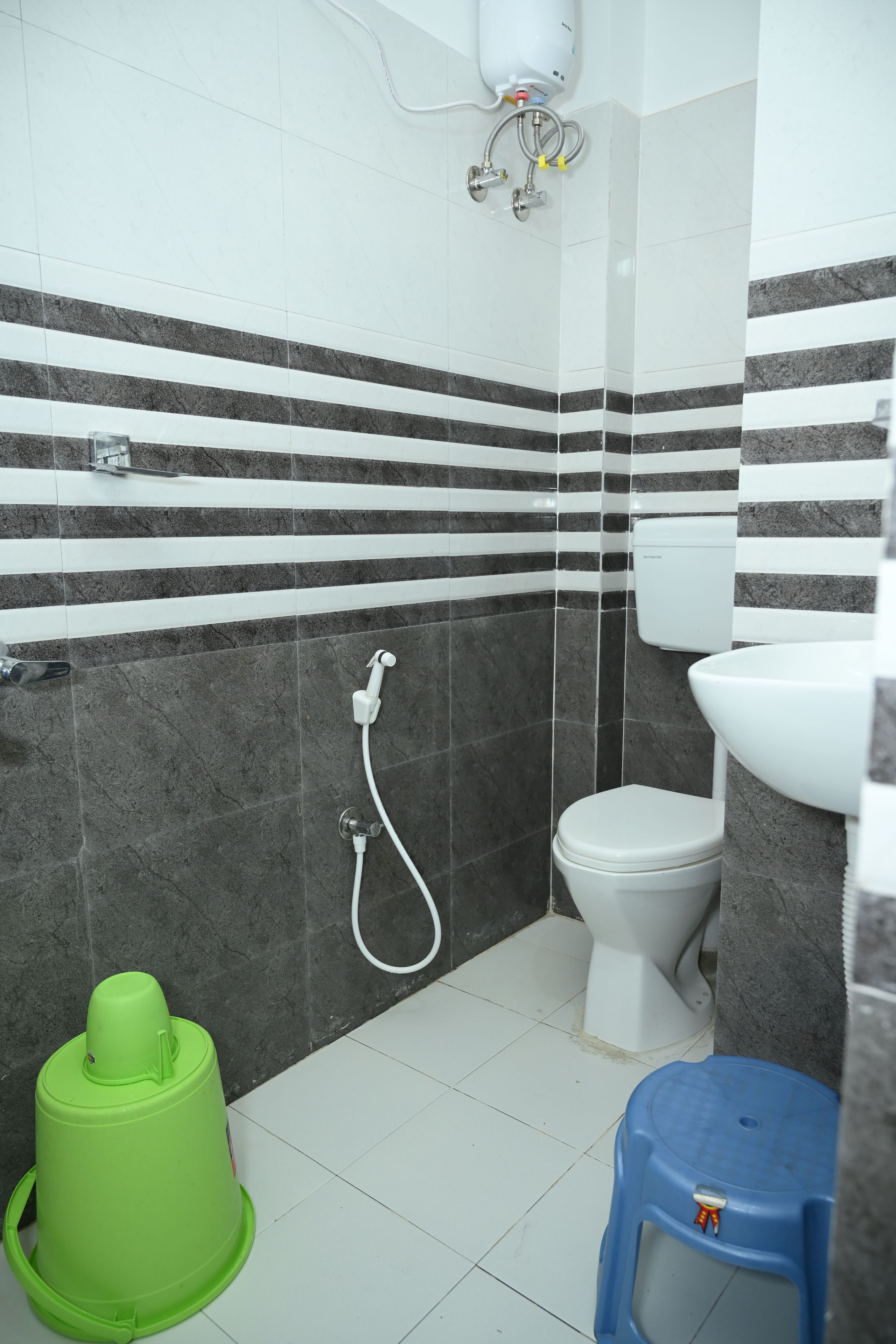 A bathroom with a toilet, a bidet, and a green bucket.