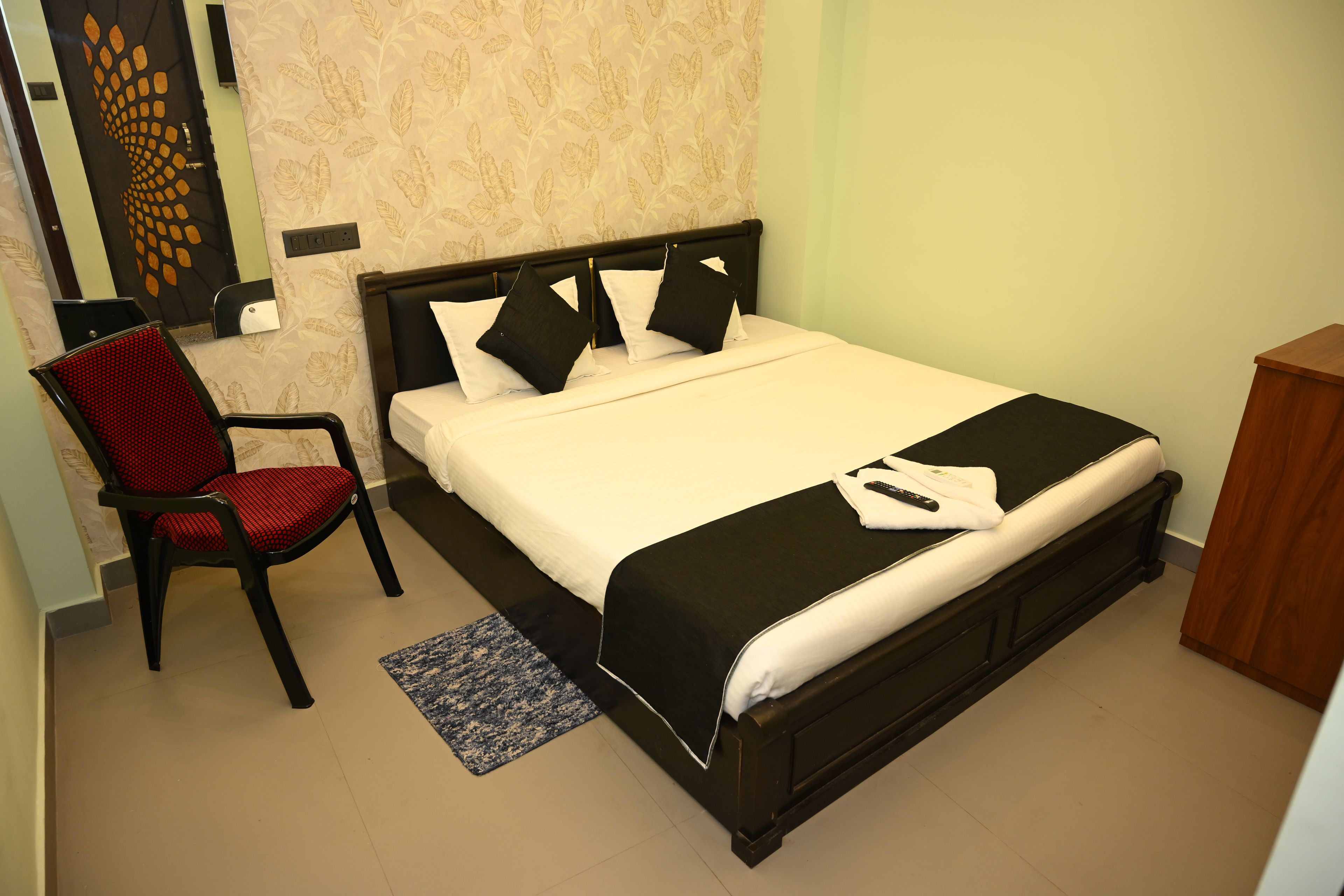 Una habitación de hotel con una cama, una silla, una mesita de noche y una alfombra pequeña.