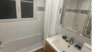 Un bany amb finestra, un lavabo, un mirall i una zona de dutxa.