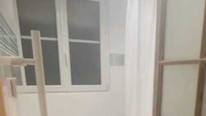 Una habitació petita i estreta amb una finestra, una escala de fusta i un armari de fusta.