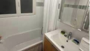Un bany amb banyera, un lavabo i un mirall.