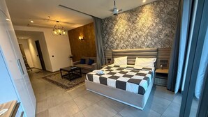 A modern bedroom with a large bed, a ceiling fan, and a patterned wallpaper. - spira.staycation (Noida)