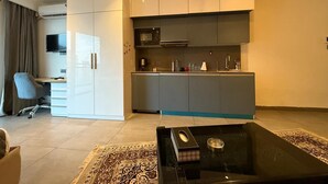 A modern living room with a black coffee table, a grey sofa, and a TV. - spira.staycation (Noida)