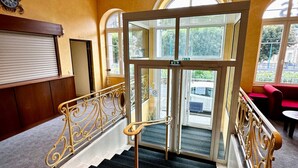 A grand staircase with ornate railings leading to a glass door entrance. - So' Amandine - La Bourboule (La Bourboule)
