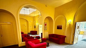 A spacious room with yellow walls, red sofas, and a large mirror. - So' Amandine - La Bourboule (La Bourboule)