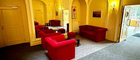 A spacious room with yellow walls, red sofas, and a large mirror.