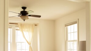 Una sala de estar con un sofá color beige, una mesa de centro de madera, un tapete estampado y un ventilador de techo.
