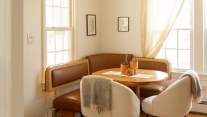 Un comedor con una mesa redonda, dos sillas, un banco y un sofá.