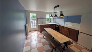 Una cocina con una isla grande, armarios de madera, horno integrado y un ventanal que proporciona luz natural.