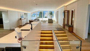 A modern kitchen with a central island, a glass staircase, and a view of the outdoors. - Modern loft for 6 with mountain views | Bad Ischl (Bad Ischl)