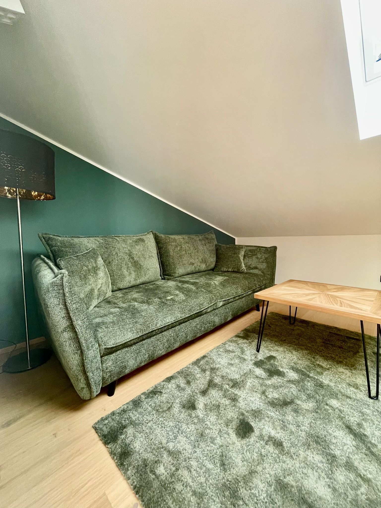 A green sofa in a room with a wooden table and a green rug.