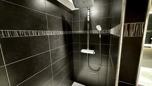 A modern bathroom with dark tiles, a shower, and a toilet. - Les Etrangers 402 - La Bourboule (La Bourboule)
