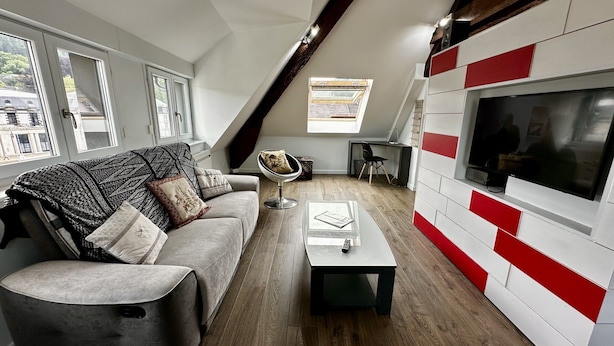 A modern living room with a sofa, coffee table, and a TV mounted on a red and white wall. - Les Etrangers 402 - La Bourboule (La Bourboule)