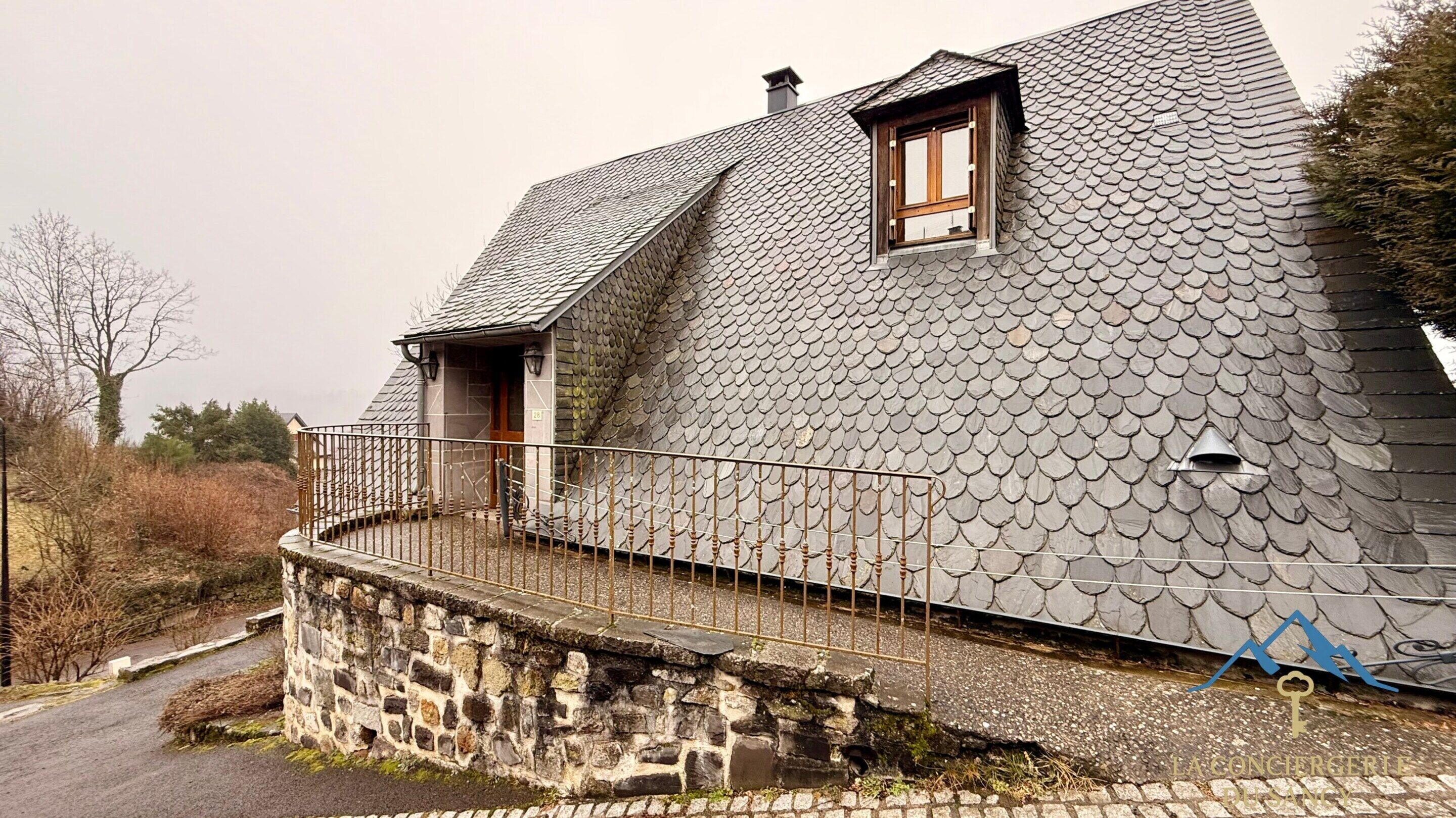 Una casa de piedra con un techo inclinado y un pequeño balcón.