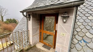 A building with a stone facade, a wooden door with the number 28, and a metal railing.