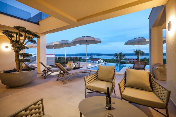 A rooftop lounge with lounge chairs, umbrellas, and a view of the ocean. - Maslenica Villa With Heated Pool (Jasenice)