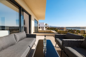 A modern balcony with a sofa and armchairs, a glass table, and a bottle of wine. - Maslenica Villa With Heated Pool (Jasenice)