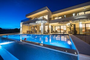 Ein modernes Hotel mit Swimmingpool, Außenbereich und einer gut beleuchteten Fassade.