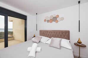 A modern bedroom with a large bed, a view through a sliding door, and a decorative wall piece. - Maslenica Villa With Heated Pool (Jasenice)
