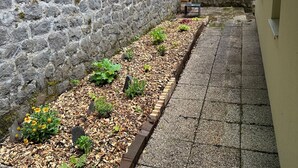 A stone wall with a garden bed, a bench, and a tiled pathway. - Villa Janchrisma - Montdore - 11pers (Mont-Dore)
