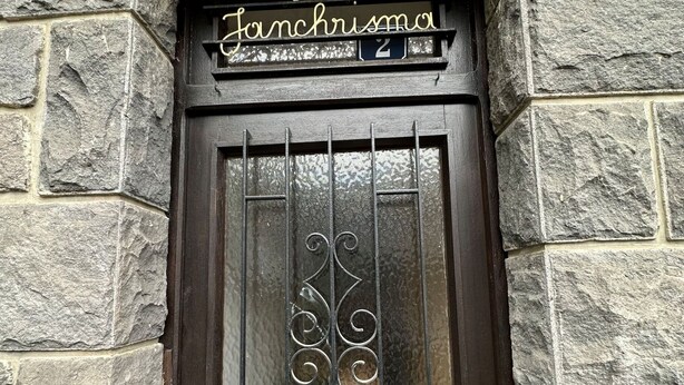 A stone building with a dark wooden door featuring a metal gate and a sign above that reads "Villa Janchrusma." - Villa Janchrisma - Montdore - 11pers (Mont-Dore)