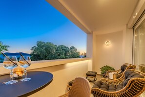 Een balkon met rieten meubels, een tafel met glazen en een kaars.