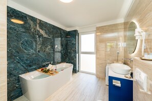 Een moderne badkamer met een vrijstaand bad, een wastafel en een grote spiegel.
