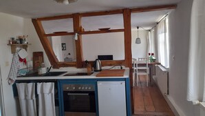 Eine kompakte Küche mit blau-weißer Farbgestaltung, Holzbalken, einem kleinen Backofen und einem Spülbecken.