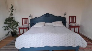 Ein Schlafzimmer mit blauem Kopfteil, zwei Nachttischen, einem Blumentopf und einem Streifen Teppich.