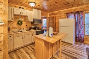 A wooden cabin kitchen with white cabinets, a microwave, a refrigerator, and a wooden island counter. - Private cozy log cabin-Your sweet spot in Smoky (Pigeon Forge)