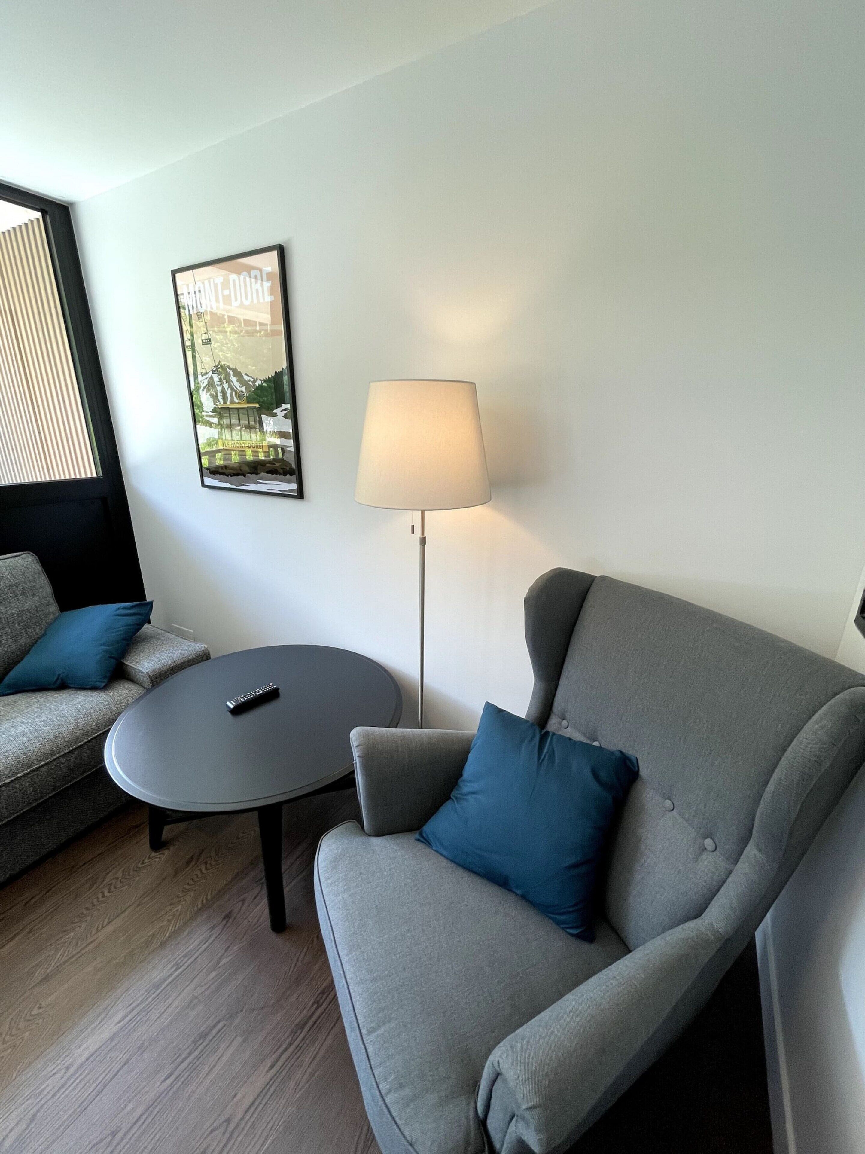 A modern living room with a grey sofa, a round coffee table, and a floor lamp.
