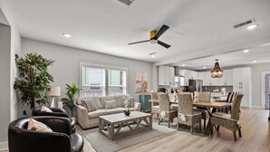 Ein geräumiges Wohnzimmer mit einer Couch, einem Couchtisch und einem Essbereich mit Stühlen.