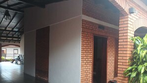 Un espacio al aire libre techado con pared de ladrillo, una puerta y suelo de baldosas.