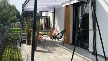A covered patio area with two chairs and a swing set.