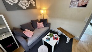 Un salon moderne avec un canapé gris, une petite table blanche et un banc en bois.