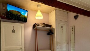 Une chambre à coucher comprenant un lit, un téléviseur fixé au mur, un luminaire suspendu et une armoire.