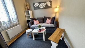 Un salon moderne avec un canapé gris, une table basse blanche et un banc en bois.