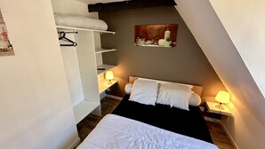 A bedroom with a bed, a wardrobe, and a nightstand with a lamp. - Practical Apartment in La Bourboule (La Bourboule)