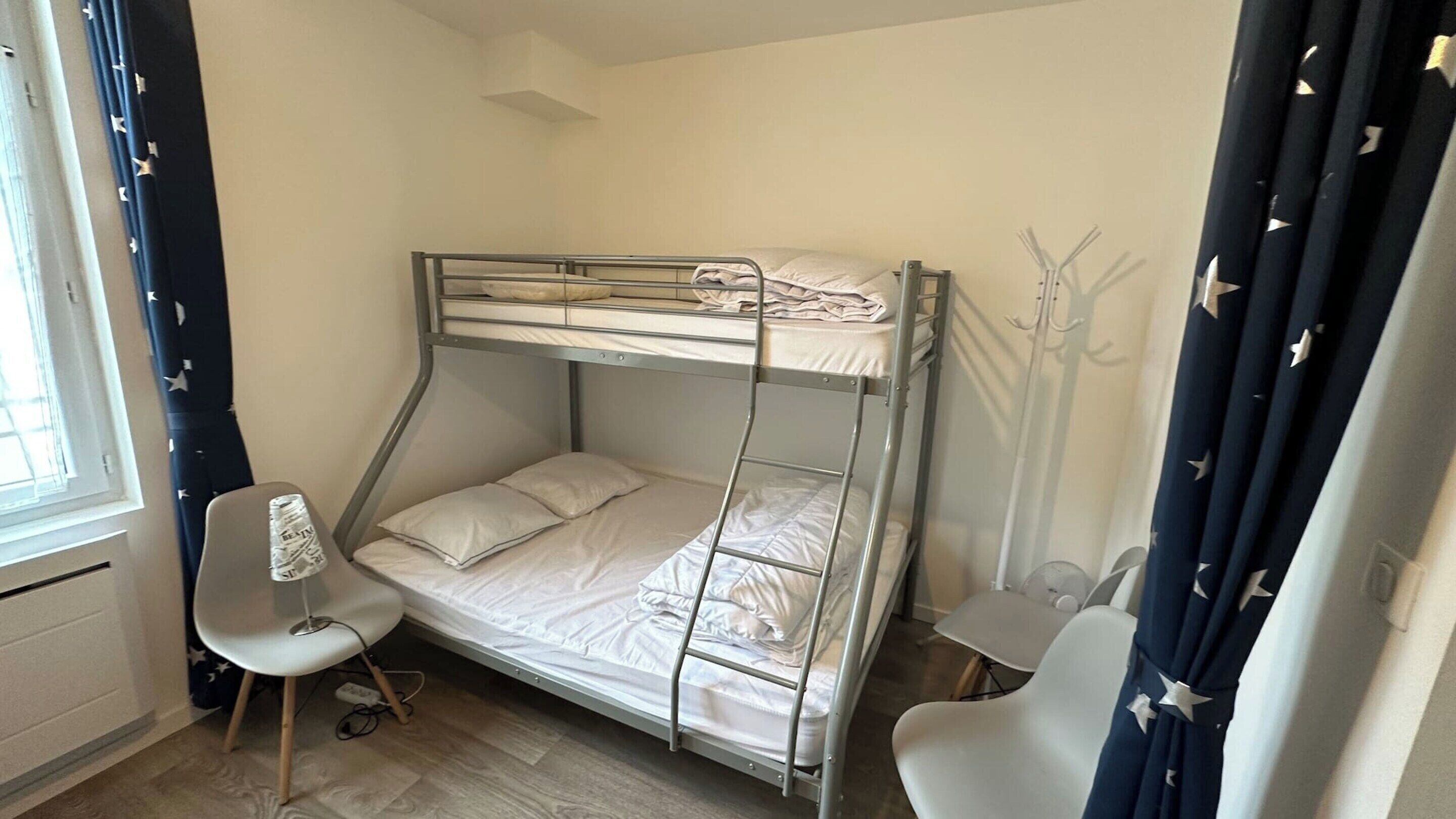 Dormitorio con literas, escritorio, silla, ventana y cortinas con diseño de estrellas.