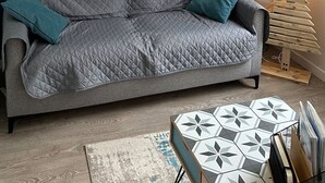 Ett modernt vardagsrum med turkosa väggar, en grå soffa och ett geometriskt soffbord.