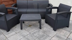 A patio area with a dark wicker sofa, two armchairs, and a small table. - Holiday Home, 4 Bedrooms, Private Garden (Ustka)
